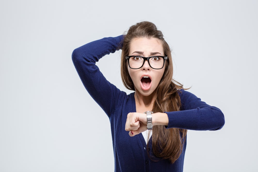 Portrait of shocked young woman holding hand with wrist watch and looking at camera isolated on a white background Portrait of shocked young woman holding hand with wrist watch and looking at camera isolated on a white background
